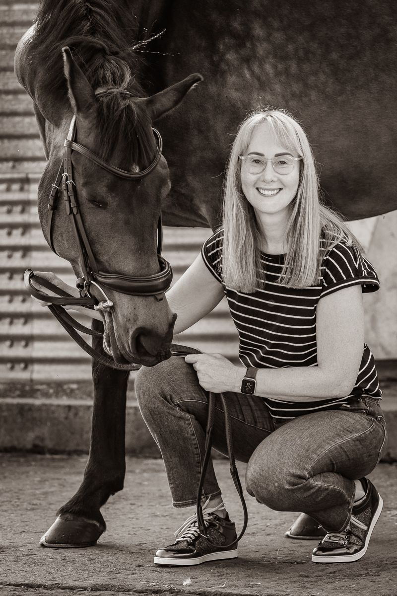 A heartwarming black and white portrait showing a close interaction between a horse and someone in a striped shirt.