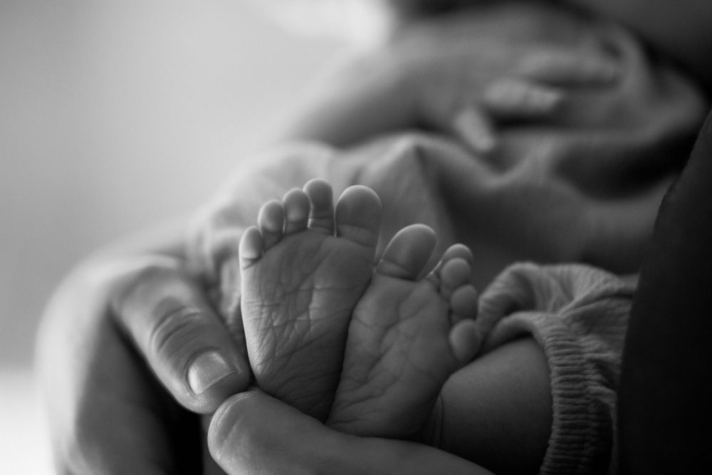Close-up of a newborn's feet cradled in a parent's hands in Mountain Home, Arkansas