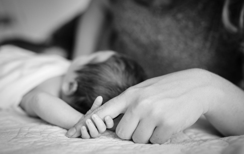 Black-and-white photo of a sleeping newborn with a parent's hand in Mountain Home, Arkansas