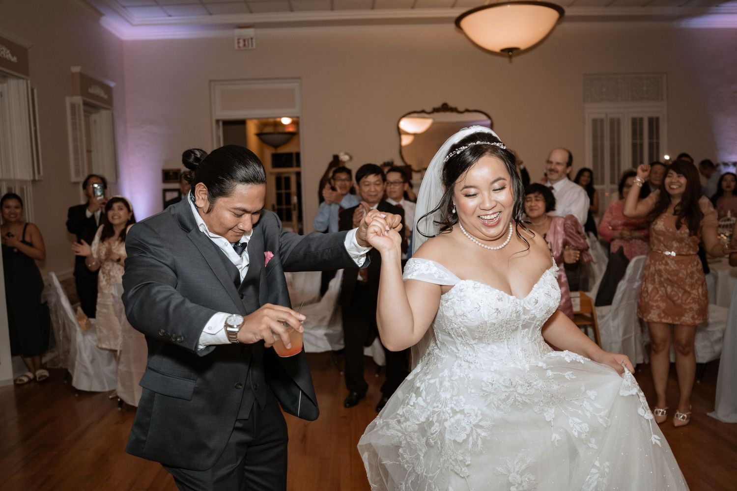 Wedding couple dances joyfully on reception dance floor.