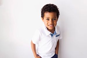 Young student in white polo shirt against white background.