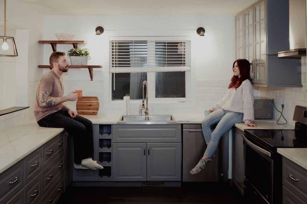 Couples photo session sitting on opposite sides of the kitchen facing each other