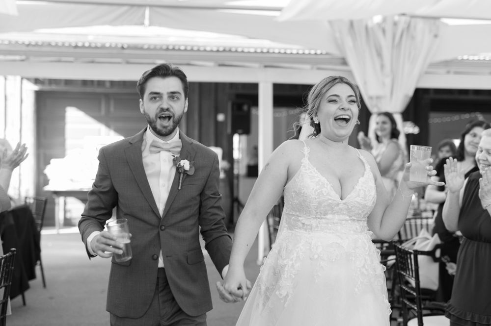 Wedding party members laugh and celebrate together in formal attire during reception festivities.