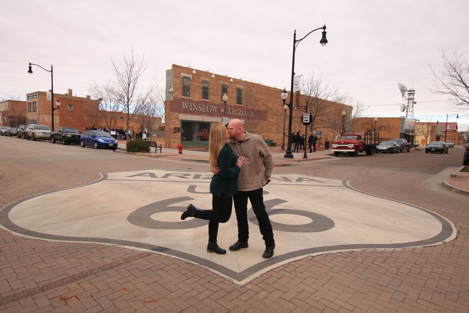 Two people standing on a decorative street intersection in a small town setting.