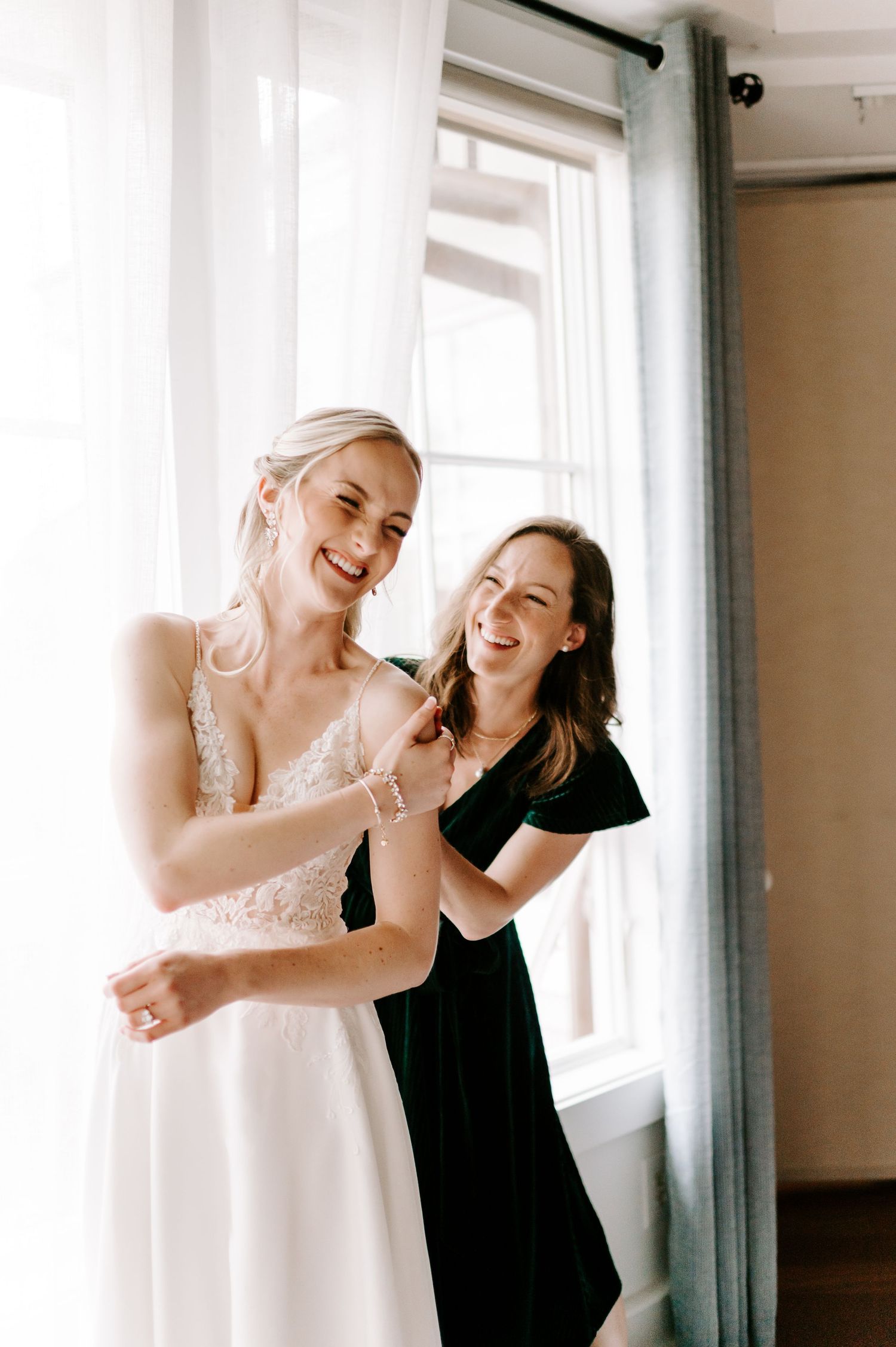 Two people sharing a joyful moment in front of bright windows.