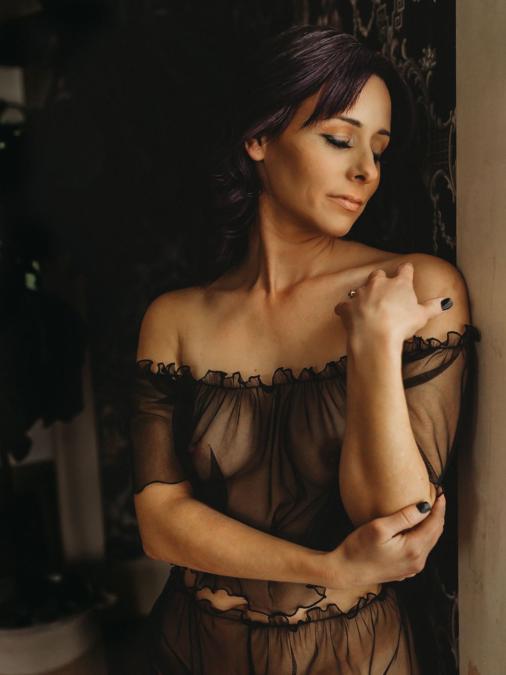 Intimate portrait in brown sheer dress against dark patterned wallpaper.