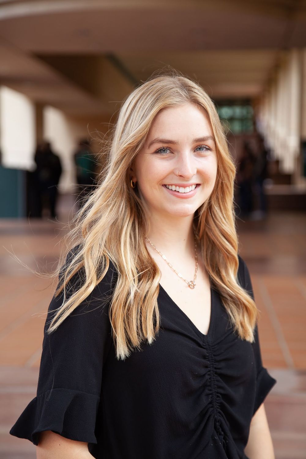 Young professional woman smiling by hallway.