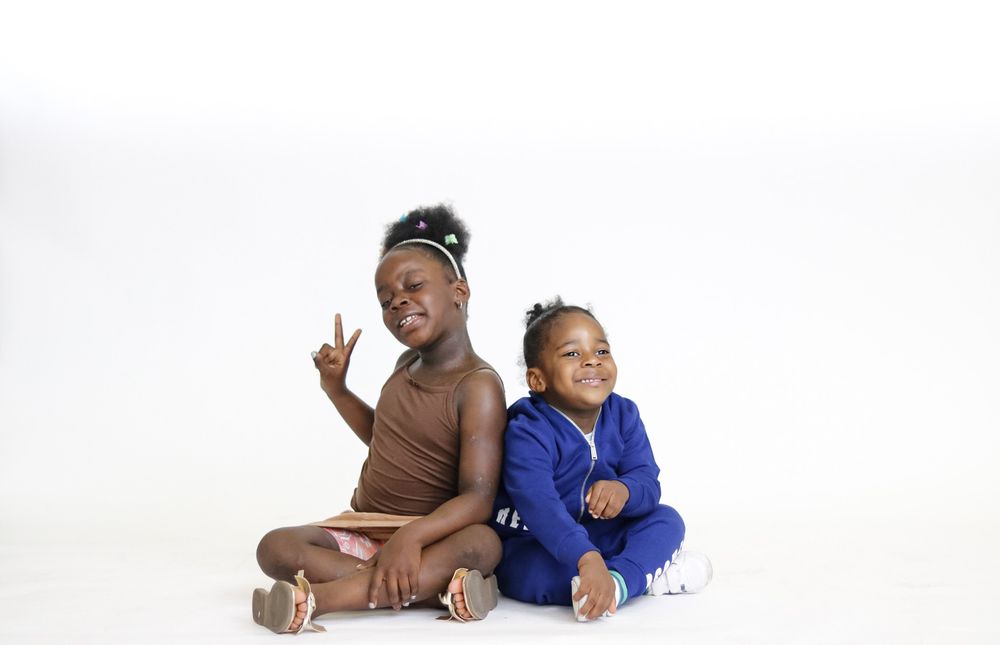 Playful family photo session with coordinating blue and brown outfits on white background.