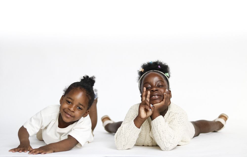 Series of playful poses of child in cream colored outfit on white background.