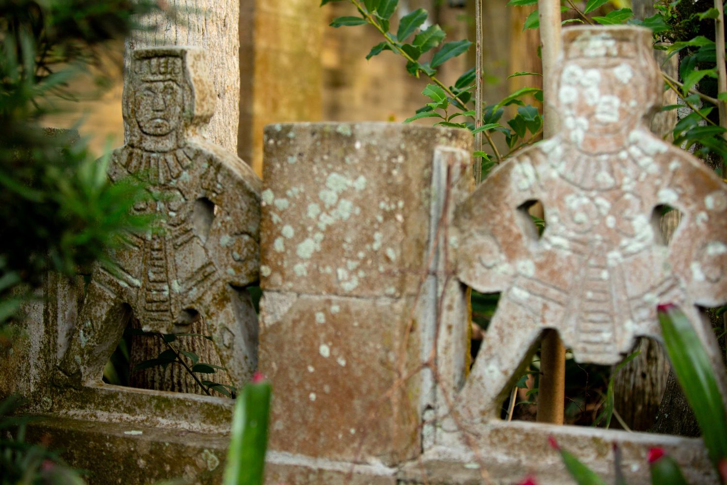 Ancient Celtic stone crosses with weathered carvings stand among green foliage in a cemetery.