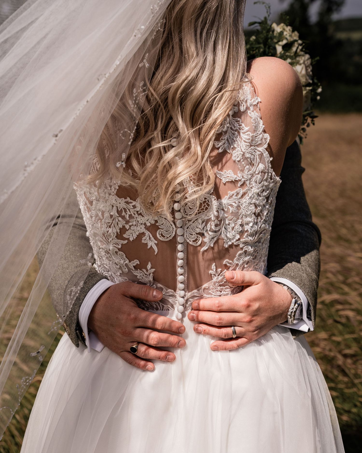 Close-up of intricate lace wedding dress buttons and sheer back detail.