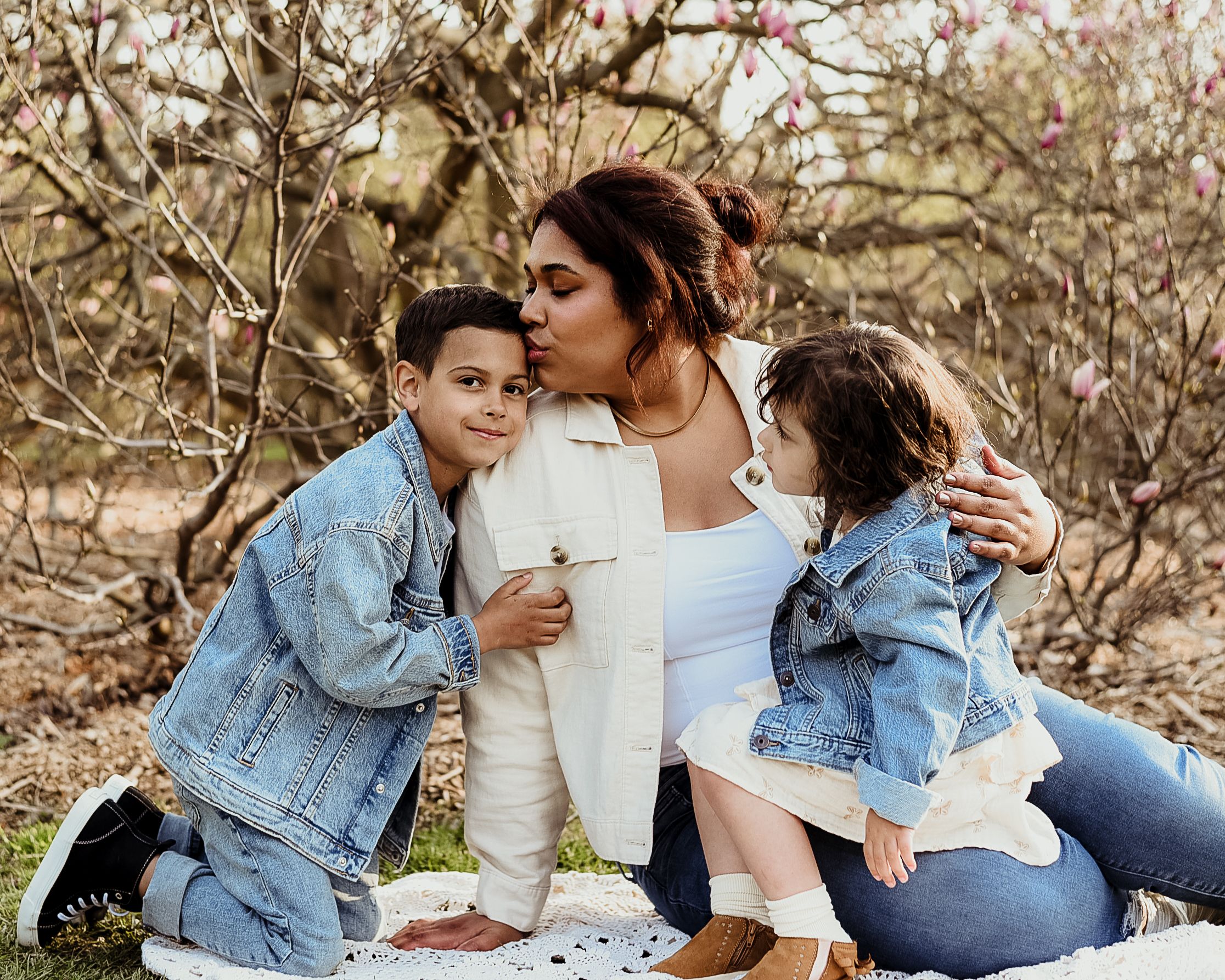 Family wearing denim jackets having picnic among blooming trees in springtime.