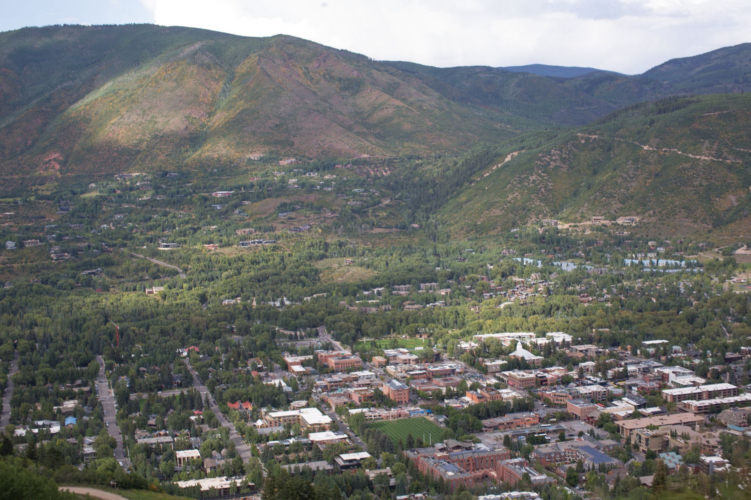 An aerial view of a mountain town nestled in a valley surrounded by green hills.