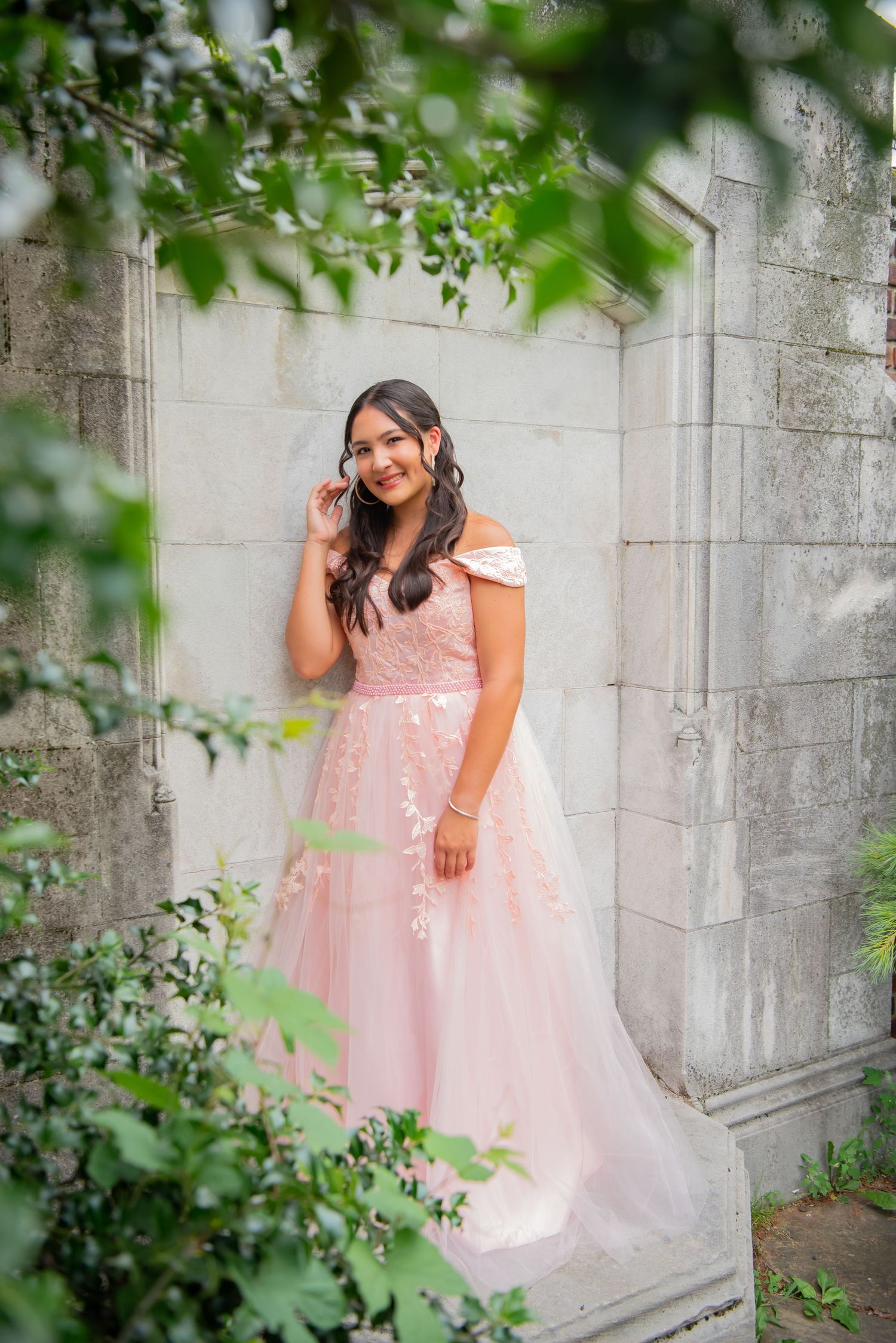 full body portrait of girl in pink gown framed with greenery at mellon park