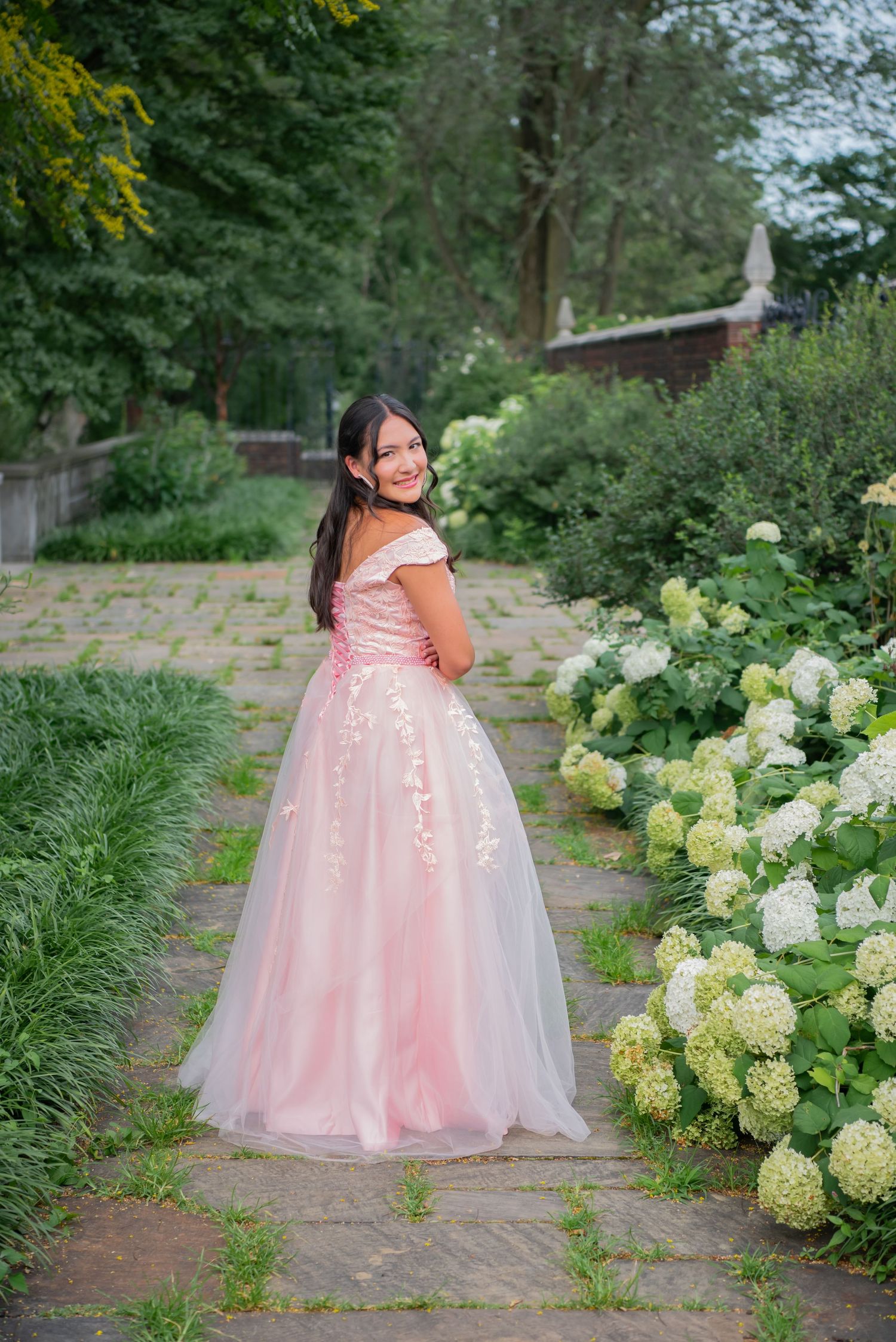 girl in pink gown walking garden path at mellon park with flowers
