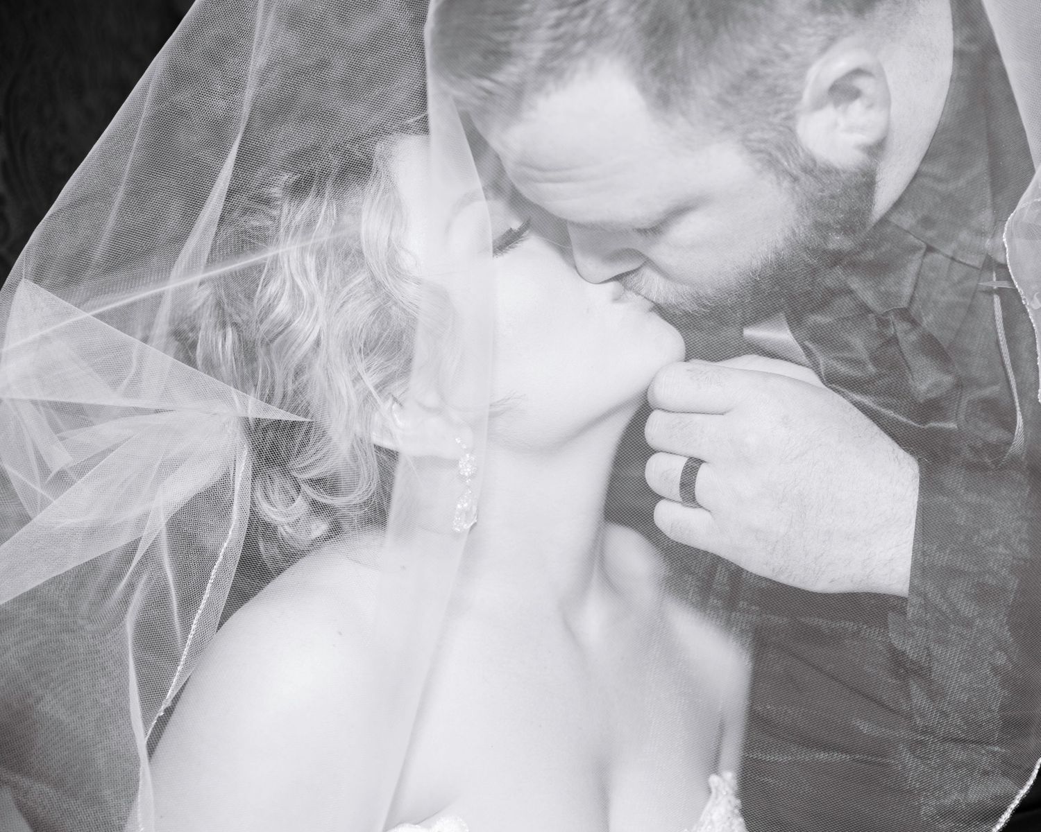Groom kissing his new bride under her vail.