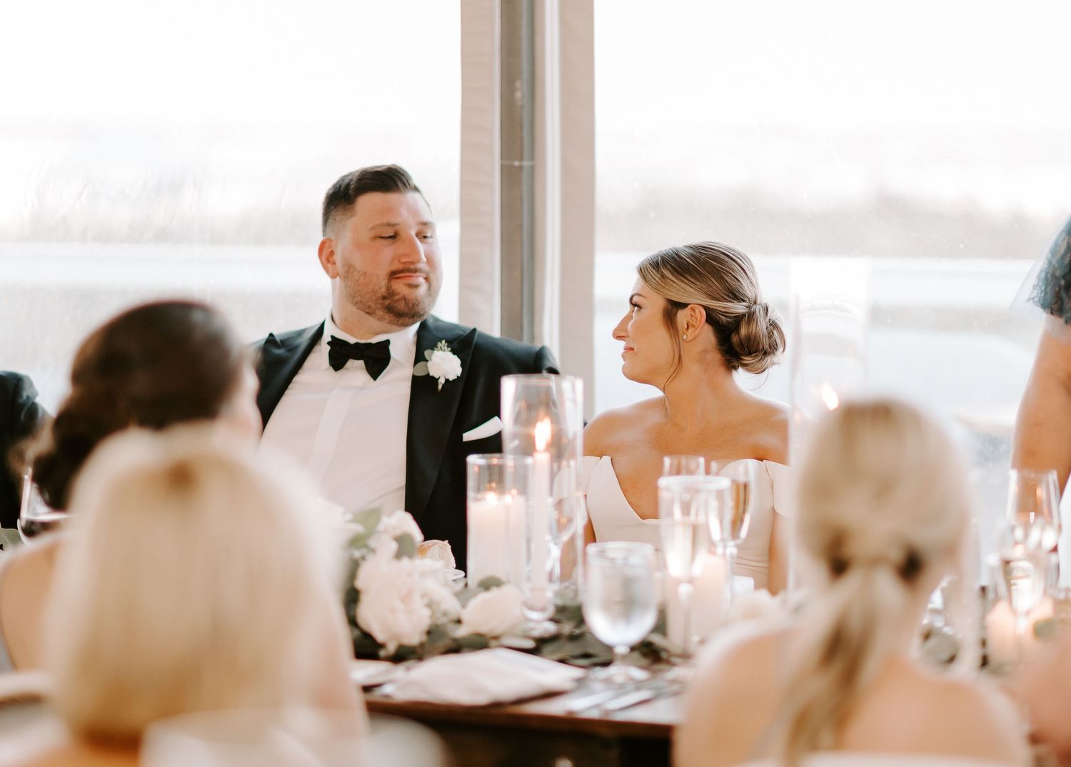 Wedding reception dining tables set with glowing candles and elegant place settings.