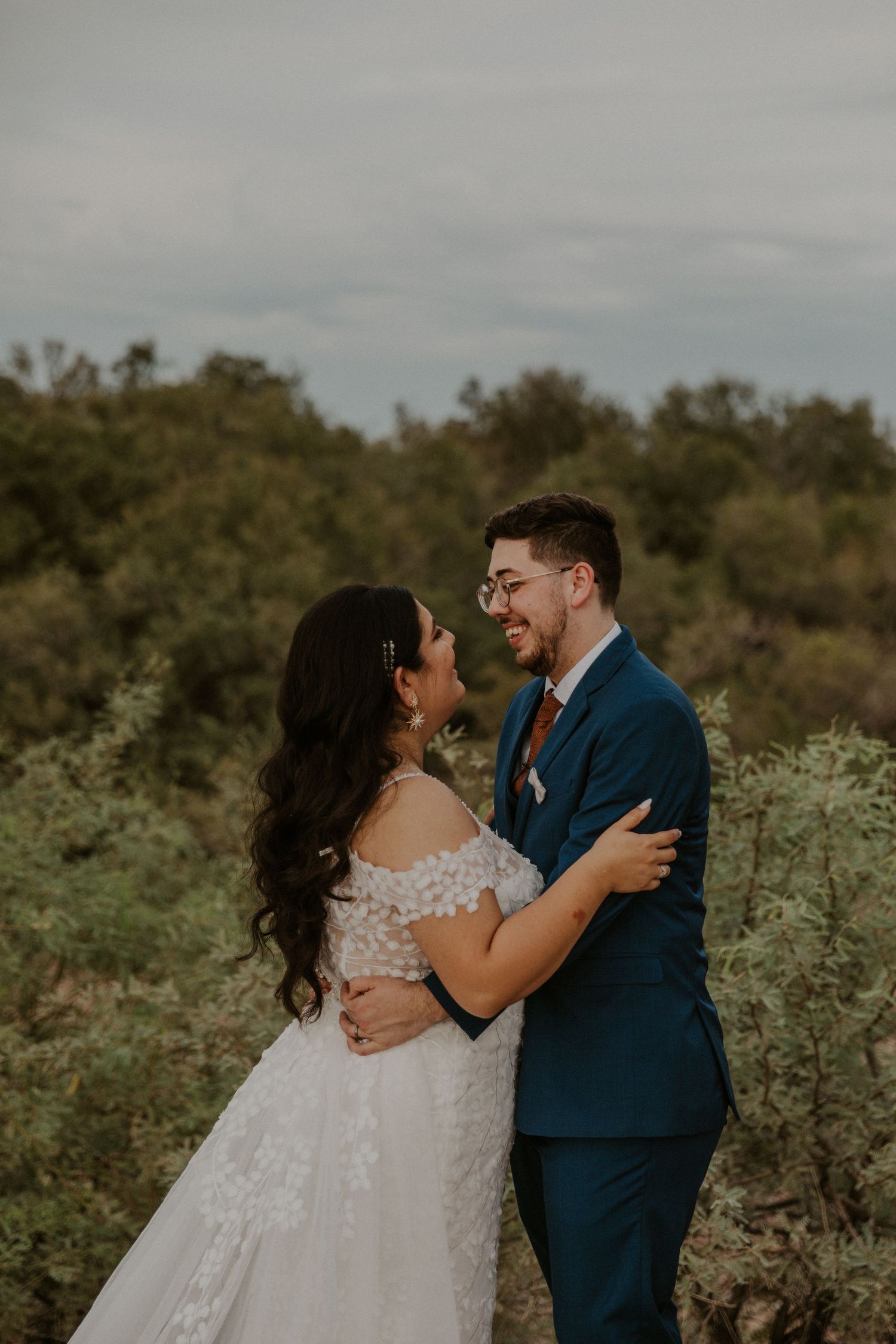 couple embracing on their wedding day with smiles on their faces in a beautiful nature enviroment