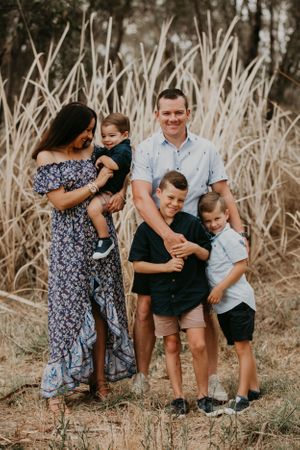 Candid family moment captured in tall grass during golden hour photo session.