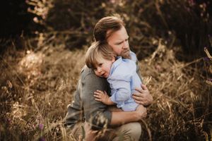 Intimate family moments captured in moody lighting among tall grass.