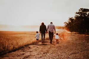A silhouette of a family walking together on a path at sunset.