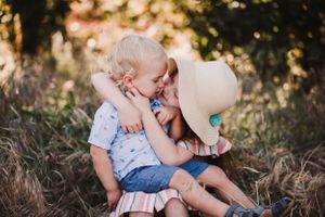 Candid family photo session in golden sunlight with playful interactions in a natural outdoor setting.