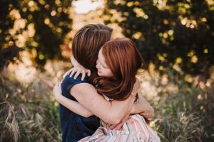 An intimate embrace captured in warm sunset lighting among tall grass.
