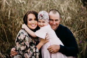 A heartwarming family portrait taken in a field of tall grass at sunset.