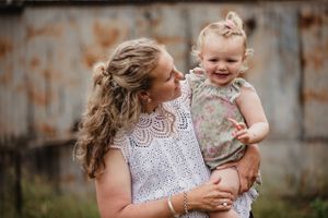 A candid moment of shared joy and laughter between parent and child against a rustic backdrop.