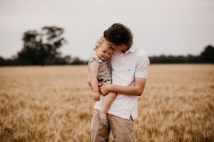 A tender moment between parent and child in a golden wheat field at sunset.