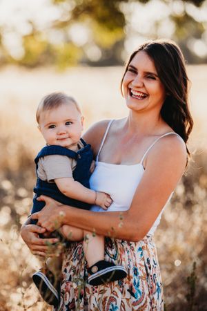 Joyful outdoor family session in field during golden hour lighting.