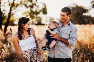 Candid family moments captured in a sun-drenched field with natural expressions.