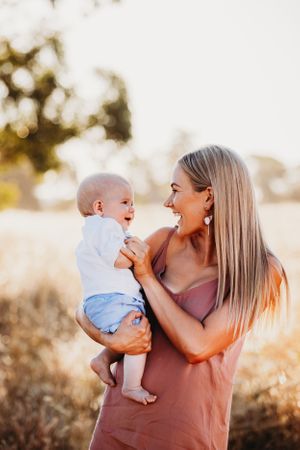 Mother and baby share joyful moments together in warm evening light.