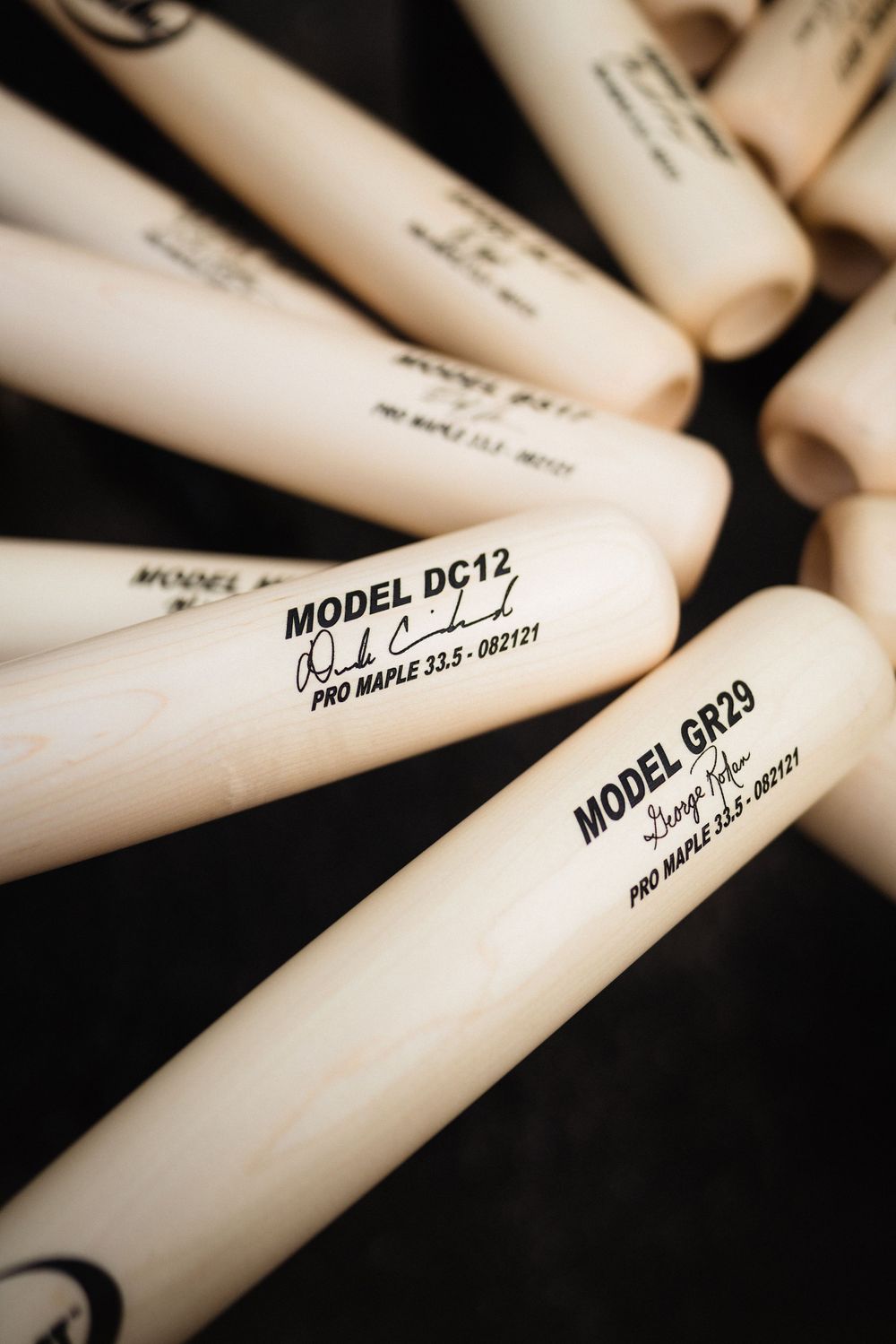 Close-up of white Pro-Mark drumsticks with model numbers displayed on black background.
