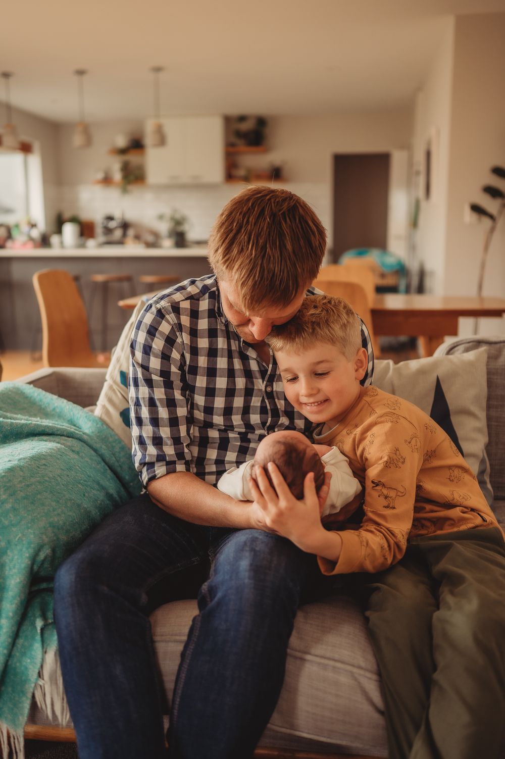 Parent and child bonding over newborn sibling on cozy couch.