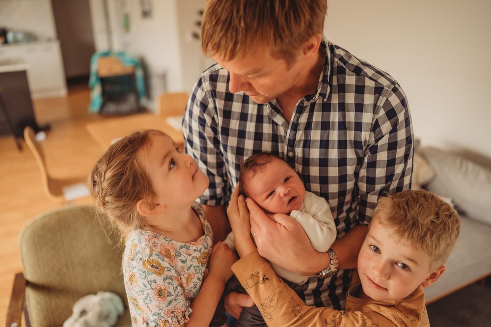Family sharing tender moment together with newborn in living room.