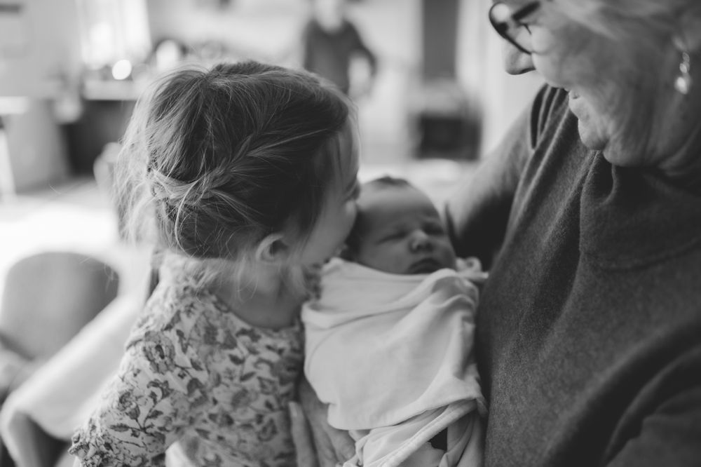 Family members gather around to meet the newest addition in black and white.