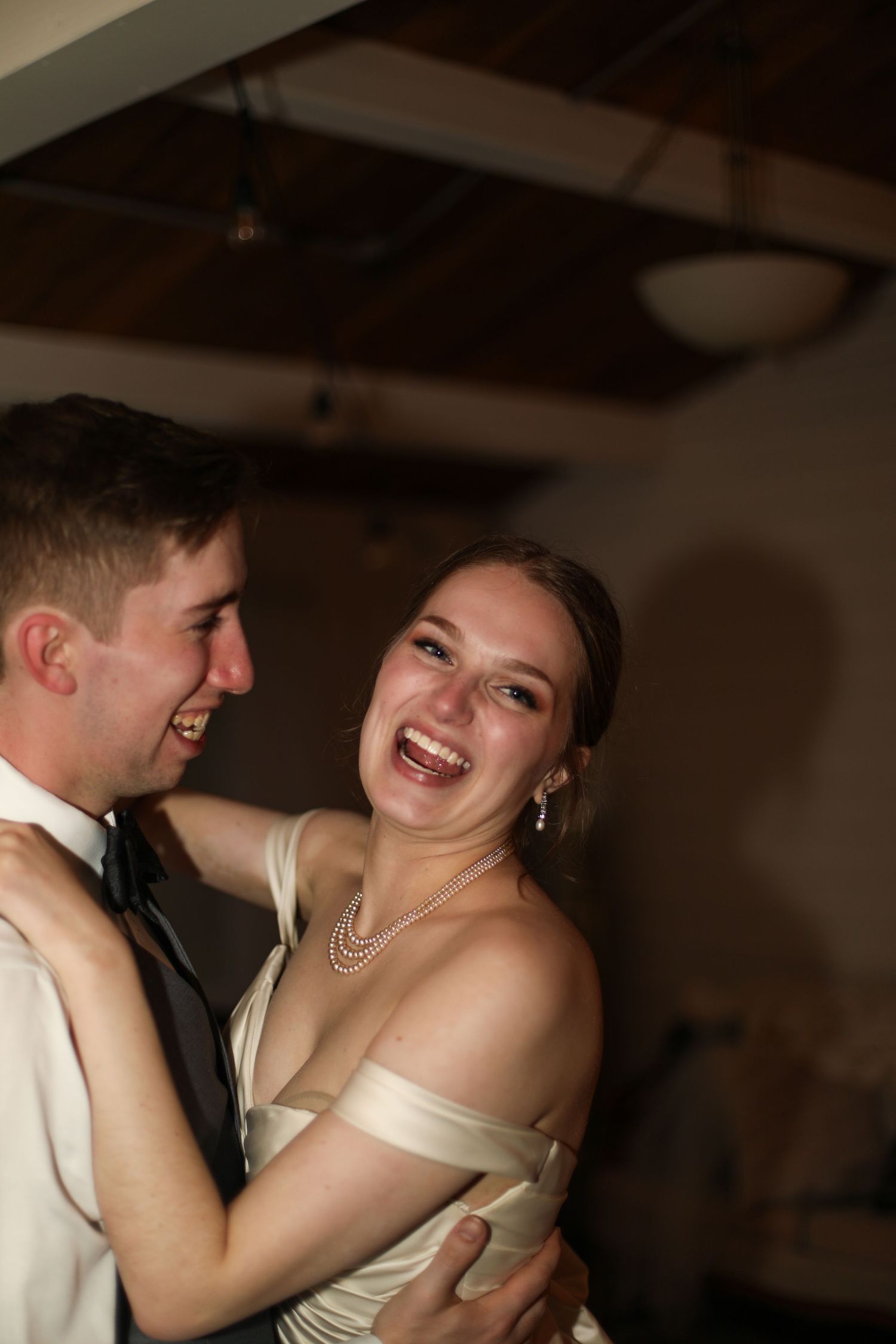 Joyful candid moment shared between newlyweds during their wedding celebration.