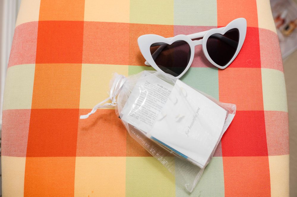 Heart-shaped sunglasses and bottle on colorful plaid background.