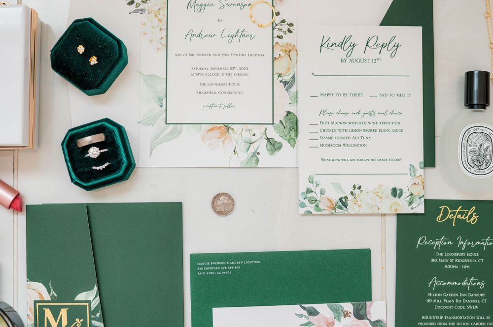 Wedding stationery suite in emerald green and white with floral designs and ring boxes.