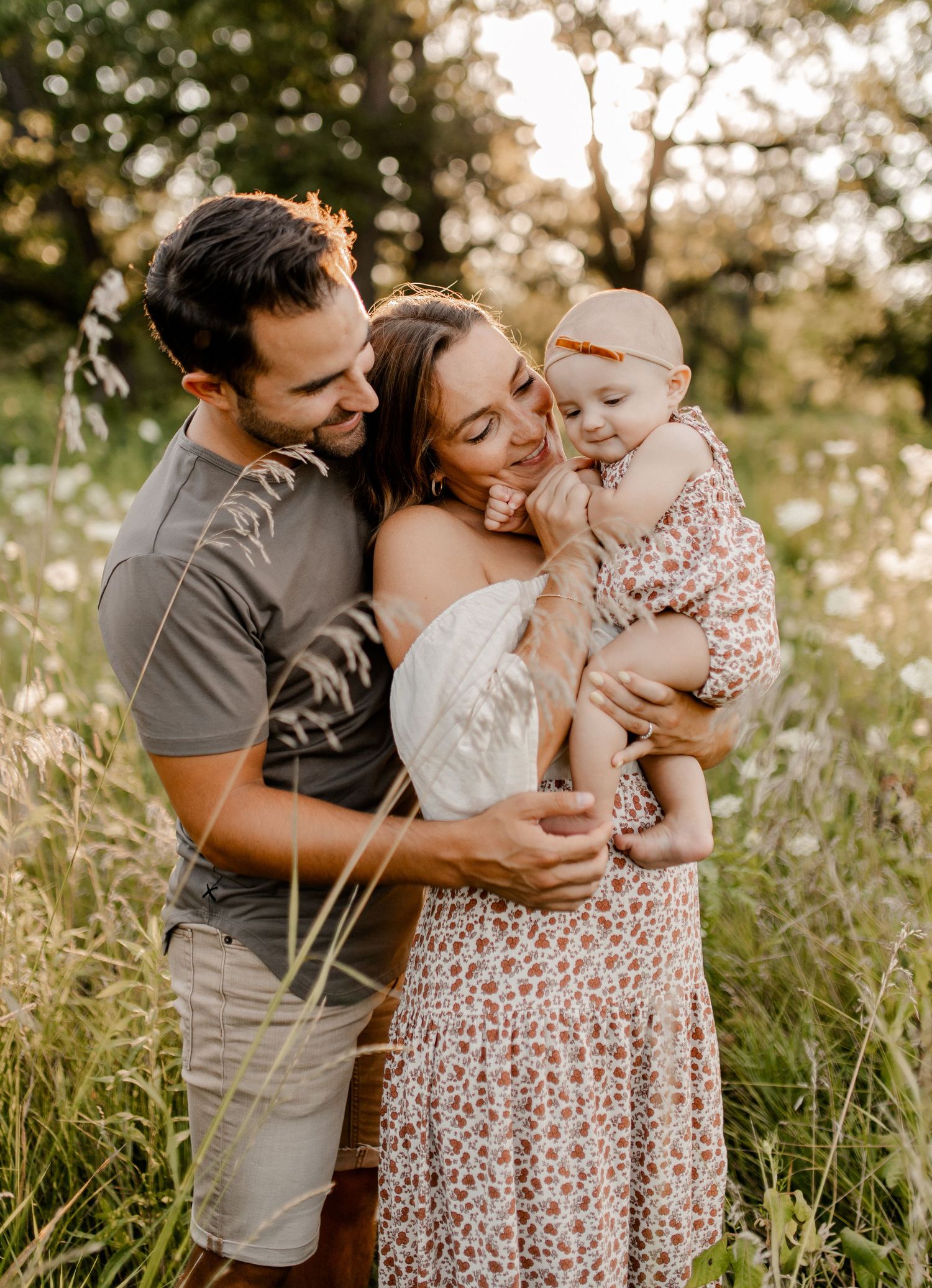 Family sharing intimate moment together in golden field at sunset.
