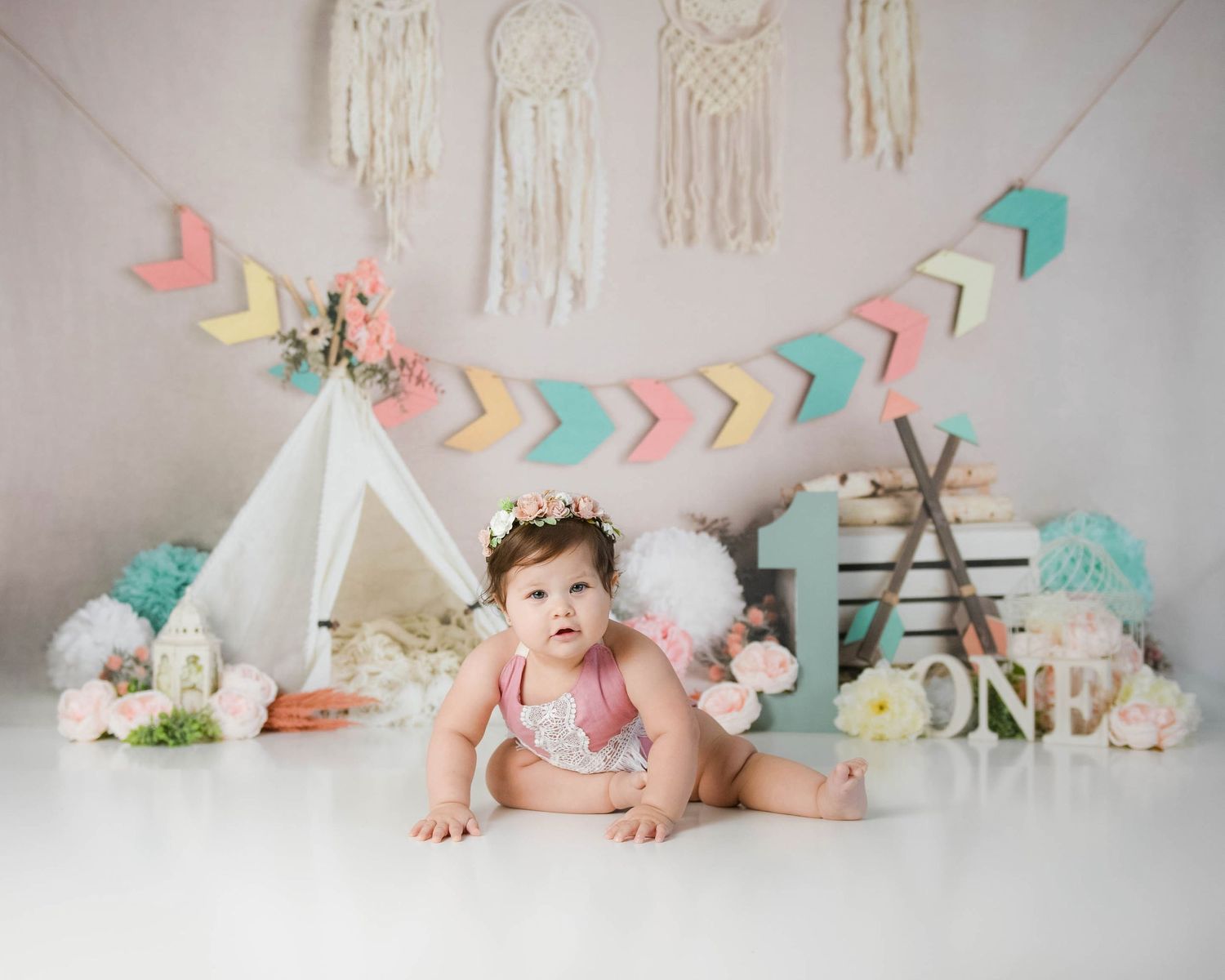one year old girl wearing pink with boho teepee behind her