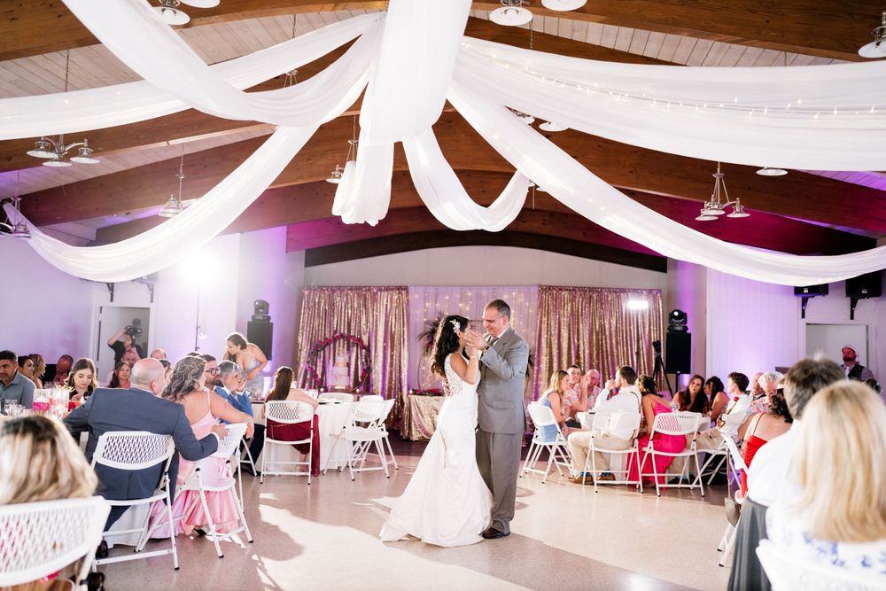 Newlyweds share their first dance under elegant white draped ceiling decorations.