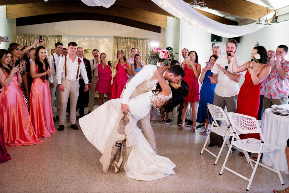A dramatic dip dance move during a wedding reception with guests in pink dresses watching.