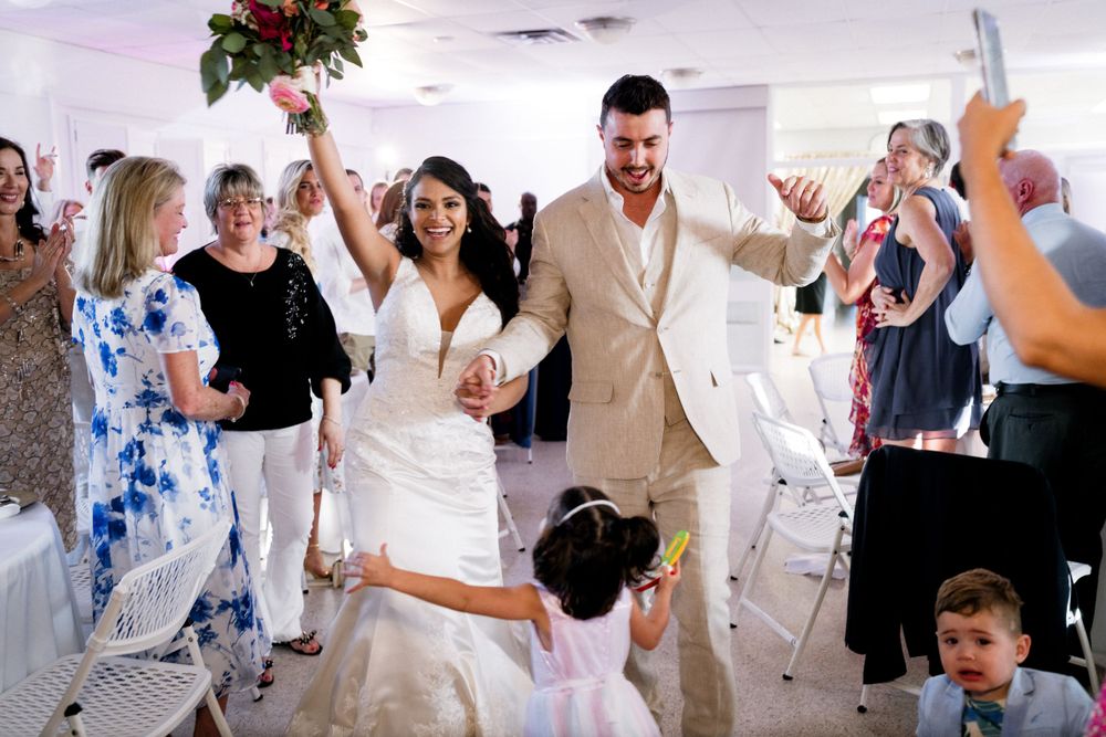 Wedding party celebrates joyously during a grand entrance at an indoor reception venue.