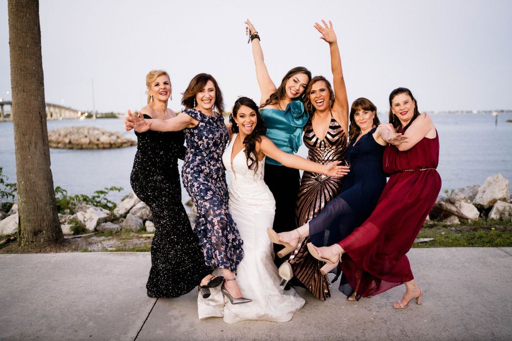 A celebratory group pose by the waterfront during wedding festivities.