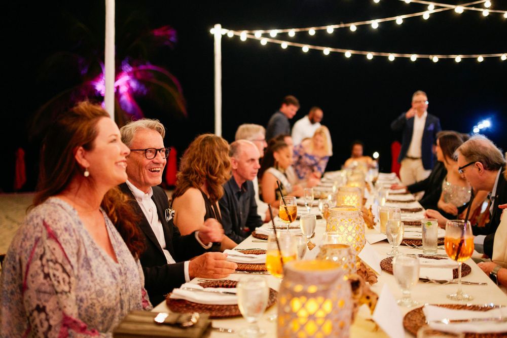 Elegant outdoor dinner party with string lights and formal table settings at dusk.
