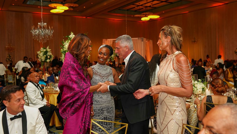 Attendees interacting during a formal celebration with festive lighting and elegant attire.