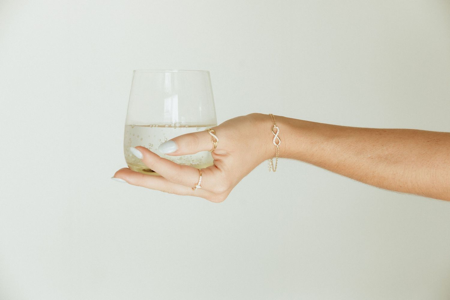 Hand holding a delicate wine glass against a neutral background.