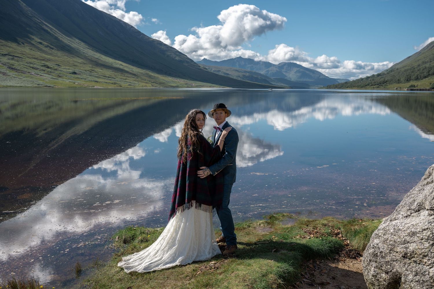 A scenic mountain lake wedding photo with perfect mirror reflections in the calm water.